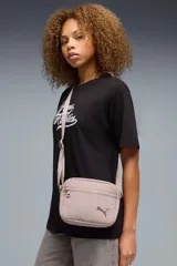 Bandolera Puma modelo 092184, color negro, de diseño rectangular con compartimento principal con cierre, bolsillo frontal con cremallera y correa ajustable para el hombro. Incluye el logo de la marca estampado en plateado.