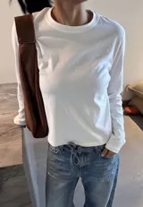 Remera de manga larga en color blanco, con cuello redondo y corte recto, confeccionada en tejido de algodón de alta calidad.