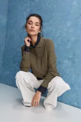 Sweater de punto color verde militar, con cuello polo y cierre frontal de botones, de manga larga con puños elastizados y diseño texturizado con relieve geométrico.