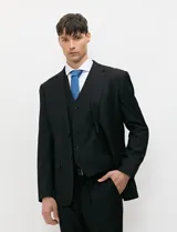 Traje de tres piezas color negro, compuesto por saco de dos botones, chaleco entallado y pantalón de corte slim, confeccionado en tejido de fantasía con spandex.