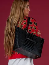 Cartera negra tipo tote bag con textura símil reptil, doble asa corta y cierre superior.