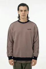 Buzo de cuello redondo en color marrón topo, con diseño de corte relajado. Presenta detalles de piping negro que recorren los hombros y las mangas, además de puños, cuello y cintura en tejido rib negro. Incluye el logo de la marca estampado en el pecho.