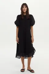 Vestido midi de corte recto color negro, con mangas cortas abullonadas, cuello redondo y detalle de volado en el ruedo.