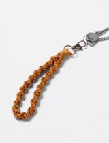 Llavero de muñeca tejido a mano con hilo color ocre y mosquetón metálico.