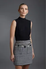 Blusa negra sin mangas con cuello alto.