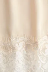 Pollera midi de corte holgado color beige, con elástico oculto en la cintura, detalle de encaje floral en el bajo y tajo lateral pronunciado.