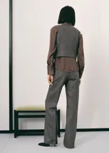 Chaleco de lana jaspeado en color gris, con cuello en V, tirantes anchos, dos bolsillos de ribete frontales y cierre delantero con botones.