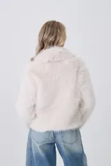 Tapado corto de piel sintética en color crema, con solapas amplias y cierre frontal asimétrico con detalles en cuero sintético oscuro.