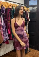 Vestido corto de tela metalizada en tono fucsia con reflejos dorados, con escote en V, diseño de top con triángulos, aberturas laterales en la cintura y doble volado irregular en el ruedo.