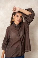 Camisa de organza blanca con cuello clásico, cierre frontal de botones y mangas tres cuartos abullonadas tipo globo con puños definidos.