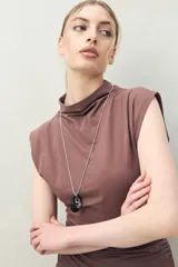 Vestido corto de punto color negro, sin mangas, con cuello cerrado y hombros levemente estructurados. Presenta frunce lateral que realza la figura.