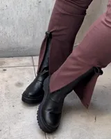 Bota de caña media negra de cuero encerado con elástico italiano en la caña de ambos lados. El fondo es de suela artesanal negra y el interior está forrado en forrería vacuna.