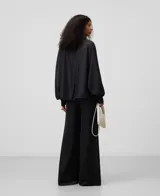 Camisa amplia semitransparente color blanco, con cuello chimenea y manga japonesa con puño. Presenta botonadura frontal oculta por solapa.