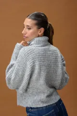 Sweater de punto con cuello alto, manga larga y diseño holgado. Presenta una textura suave con un sutil acabado brillante.