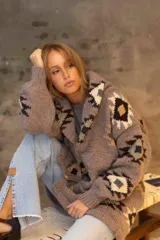 Saco tejido a mano con diseño de guardas étnicas en tonos tierra, crudo y negro. Presenta cuello solapa amplio, mangas largas con puños acanalados y cierre frontal.