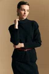 Polera de cuello alto confeccionada en tejido de punto negro, con diseño de textura acanalada en cuello, puños y ruedo, y trama vertical en mangas y espalda.