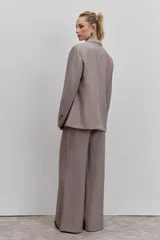 Blazer de corte sastrero con diseño cruzado y cierre de doble botonadura frontal. Presenta solapas clásicas y bolsillos laterales con solapa, confeccionado en tela con estampado de cuadros pequeños.