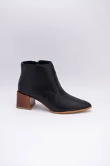 Botas cortas de cuero color beige, con punta fina y cierre lateral. Tienen un taco cuadrado de madera.