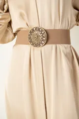 Cinto plateado de malla elástica con hebilla metálica circular bordada en piedras y strass.