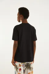 Remera negra de corte amplio, cuello redondo y mangas cortas, con estampado frontal alusivo a la playa y la marca Farm Rio.