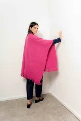 Ruana tejida color fucsia con flecos en el borde inferior.