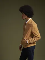 Campera bomber color camel de gamuza, con cierre frontal y bolsillos laterales.
