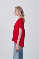 Blusa de poliéster color blanco con cuello en V, mangas cortas con dobladillo y corte holgado.