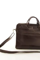 Portafolio de cuero vacuno marrón, con doble asa superior, correa ajustable desmontable y bolsillo frontal con cierre. Presenta detalles de textura símil reptil en la parte superior.