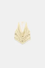Top halter color amarillo claro con escote drapeado, detalle de abalorios y lentejuelas con brillo y cierre ajustable en el cuello y la espalda.
