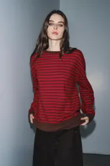 Jersey de punto con diseño a rayas horizontales en color rojo y marrón. Presenta cuello redondo, manga larga con puños ajustados y ruedo acanalado.