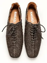 Zapato plano marrón de cuero vacuno con textura granulada, diseño acordonado de perfil bajo y suela fina.