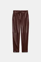 Pantalón tobillero de tiro medio color marrón oscuro, con cintura elástica ajustable con cordón y herretes dorados. Incluye bolsillos delanteros y bolsillos de plastrón en la espalda.