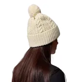 Gorro de punto de Columbia color beige con sutiles tonos amarillo claro, diseño trenzado, dobladillo vuelto y pompón superior a juego. Cuenta con una pequeña etiqueta de cuero sintético con el logo de la marca en el lateral.