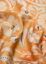 Pañuelo cuadrado de poliéster en tono naranja, con un diseño estampado que combina motivos florales y patrón paisley en blanco y celeste.