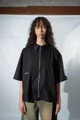 Camisa negra de manga corta con cierre frontal y cuello clásico.