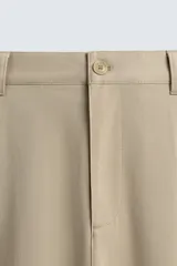 Pantalón de corte recto confeccionado en tejido elástico, con cintura elástica, pliegues frontales, bolsillos laterales y bolsillos traseros de vivo con botón.