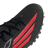 Championes de fútbol Adidas modelo F50 Club, color negro con detalles en rojo vibrante. Presentan un diseño aerodinámico con cordones y textura en la superficie para un mejor control del balón.
