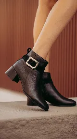 Bota corta de cuero color chocolate, con diseño minimalista, taco cuadrado de 4 cm y una hebilla metálica decorativa en el tobillo sobre una banda de gamuza.
