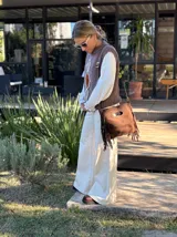 Chaleco tejido de punto en color chocolate, con cuello redondo y diseño sin mangas. Presenta un aplique frontal decorativo compuesto por tres figuras en forma de rombo en tonos tierra, bordeadas con hilo crudo.