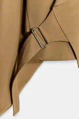 Chaqueta corta de Zara confeccionada en mezcla de algodón, con cuello solapa, manga larga con hombro caído y puños elásticos. Presenta un diseño cruzado con cierre de hebilla metálica lateral y forro interior a tono.