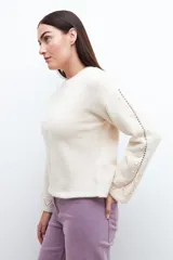 Sweater color beige claro con cuello redondo y detalle calado en el frente y mangas. Corte holgado.