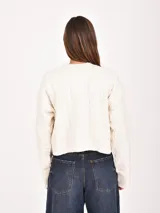 Buzo de punto color blanco hueso, con cuello redondo, mangas largas y diseño de trenzas.