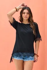 Remera negra de corte asimétrico, con mangas cortas y detalles de encaje en el dobladillo y las mangas.