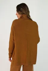 Sweater de punto color tostado, con cuello alto, diseño holgado y costura central vertical visible.