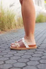 Sandalias bajas de cuero marrón y beige con tiras ajustables con hebilla.