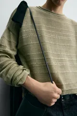 Jersey relaxed fit de punto ligero color verde claro, con rayas horizontales en un tono más claro. Tiene cuello redondo amplio, manga larga y acabados en rib.