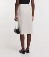 Falda midi color crema, de corte recto, con bolsillos laterales y cierre frontal.