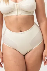 Trusa tiro alto color piel, confeccionada con tela que contiene fibra LYCRA®. Reforzada en su interior delantero para brindar mayor sujeción y contención a la zona abdominal baja. Fundillo en algodón 100%.