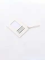 Billetera blanca con textura de cocodrilo, cierre de cremallera superior y un bolsillo frontal con solapa y botón a presión. Incluye una correa lateral para la muñeca.