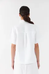 Camisa clásica blanca de manga corta, con cuello camisero y cierre frontal de botones.